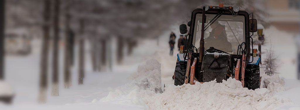 tracker removing snow on a sidewalk