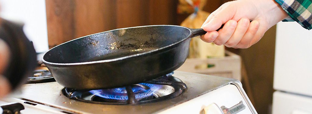 Cooking with a cast iron pan on a stove with an open flame