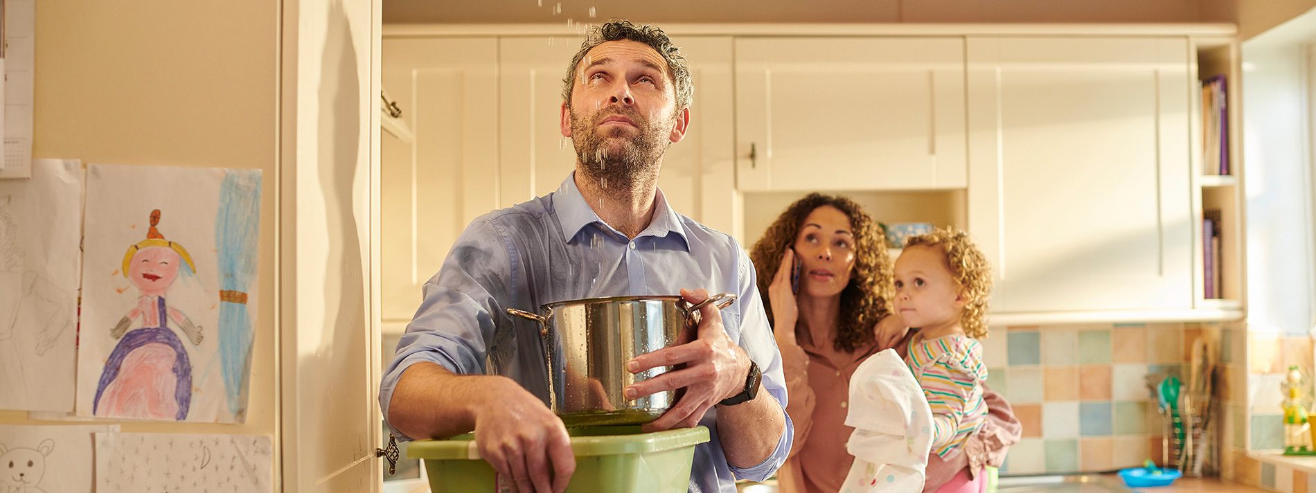 family with a water leak in the house, using pots to catch the water